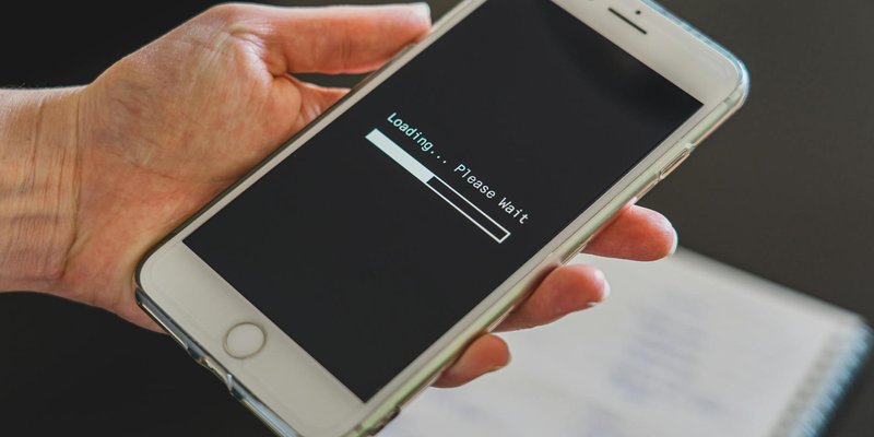 Close-up of a hand holding a smartphone with a loading screen displayed, showcasing technology usage