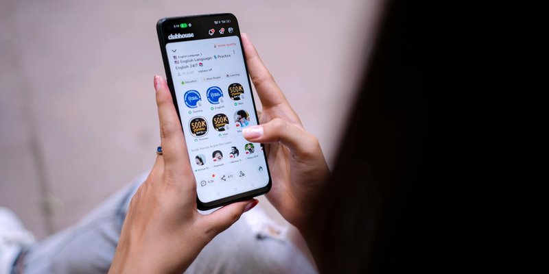 Close-up of a woman using a smartphone with social media app open. Hands holding device.