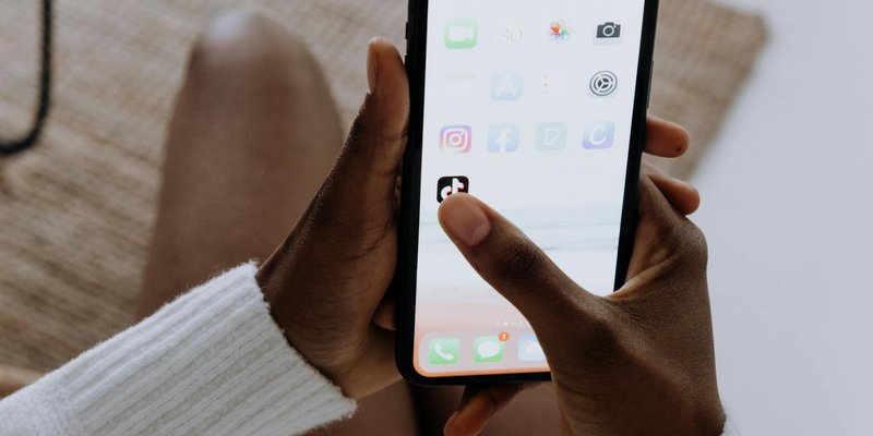 Close-up of hands with a smartphone using the TikTok app indoors, reflecting modern mobile technolog