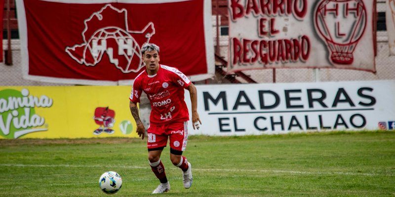 Soccer player in red uniform dribbling the ball during a football match in an outdoor stadium.
