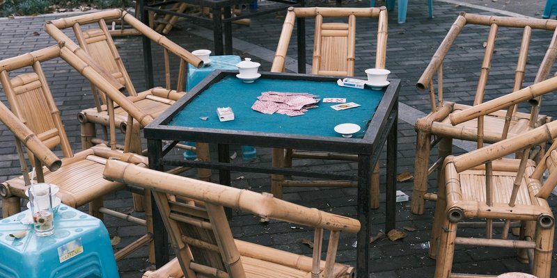 Bamboo chairs surrounding a poker table outdoors, suggesting a casual gathering or game setting.