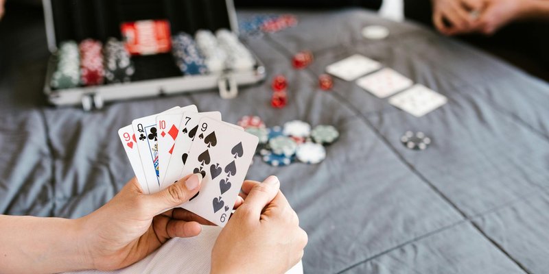 Close-up of a poker game with playing cards and chips on a table. Focus on player's hand.