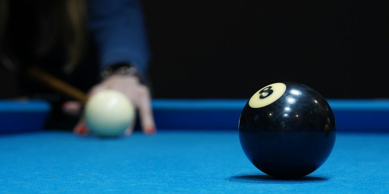 Focused view of the eight ball and cue ball on a blue pool table, ready for a shot.