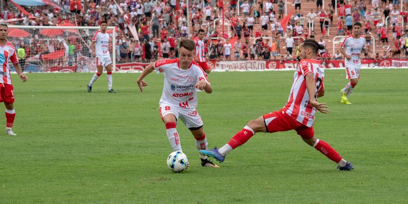 Players in action during a competitive soccer match with a vibrant crowd in the stadium.