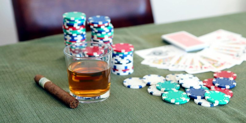 A poker table with chips, cards, whiskey, and cigar, creating a classic game night ambiance.