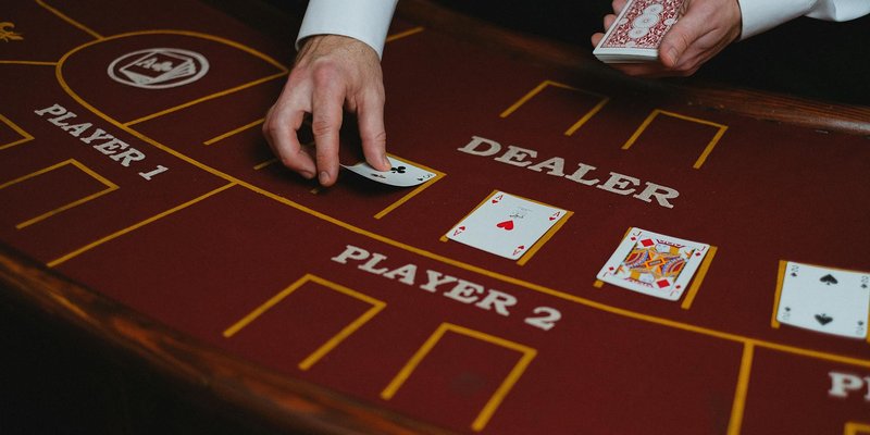 A casino dealer distributes playing cards at a poker table, ready for a game.