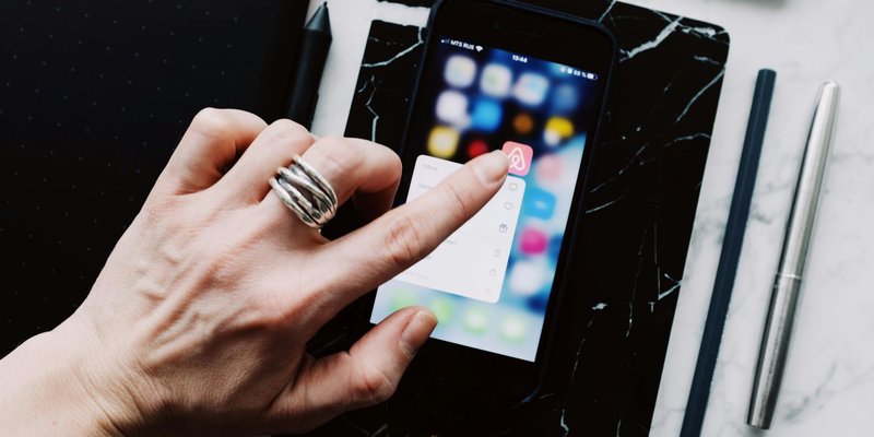 Top view of anonymous person using smartphone app tapping on screen while working with digital devic