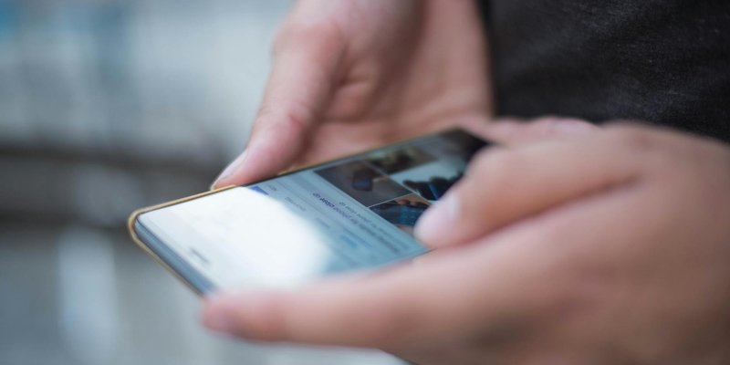 Close-up of hands using a smartphone with a touchscreen, emphasizing mobile technology.