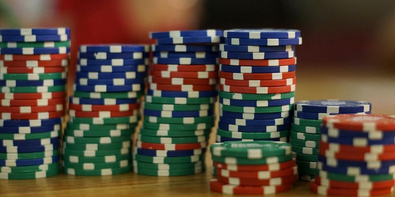 A close-up view of colorful stacked poker chips on a wooden table, perfect for casino themes.
