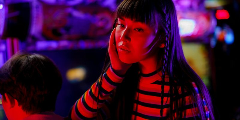 Young woman in neon lights at an arcade, enjoying a vibrant gaming experience.