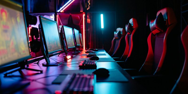 An immersive gaming room with neon lights, computers, and gaming chairs ready for a tournament.