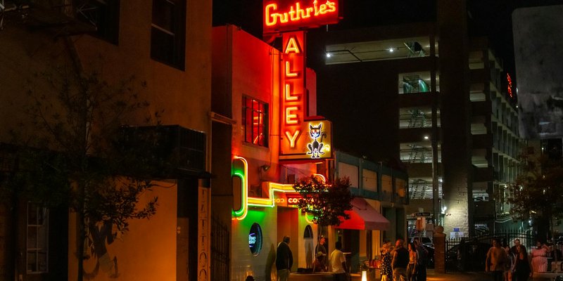 Vibrant night street scene with neon signs at Bakerville's Guthrie's Alley Cat.