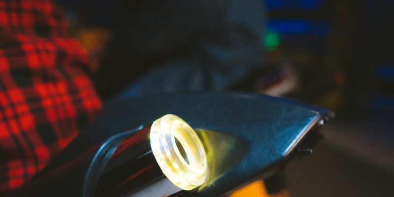 Close-up of an illuminated arcade game joystick in a dark gaming environment.