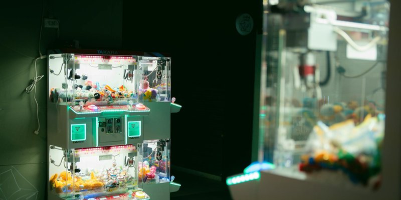 Dimly lit arcade featuring claw machines with vibrant neon lighting, capturing modern leisure and ga