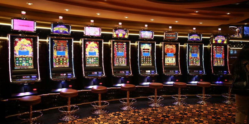A row of luxury slot machines in a casino interior with plush stools, perfect for gaming enthusiasts
