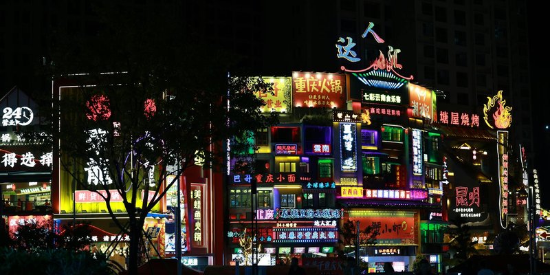 Colorful neon signs illuminate the bustling night street in an Asian city, showcasing lively nightli